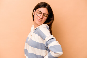 Young hispanic woman isolated on beige background suffering a back pain.