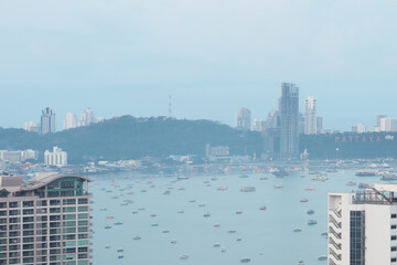 Morning peaceful open aerial view image of Pattaya bay in Thailand with skyscrapers, boats and scenic view of mountain, sea and blue sky for travel industry advertising background.