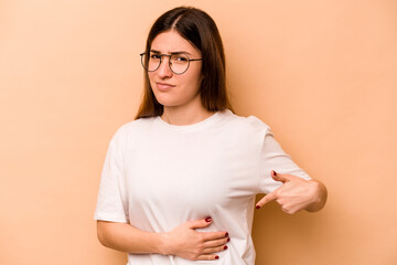 Young hispanic woman isolated on beige background having a liver pain, stomach ache.