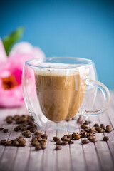 A cup of hot coffee with milk with coffee beans