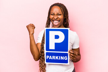 Young African American woman holding parking placard isolated on pink background