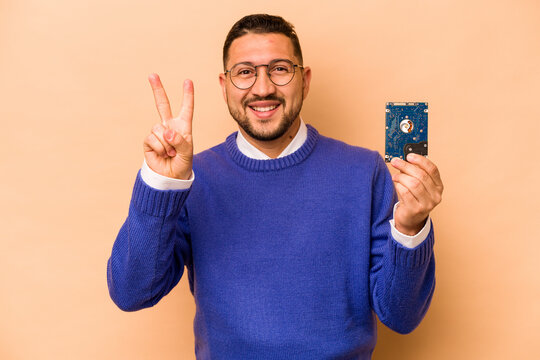 Hispanic informatic man isolated on beige background showing number two with fingers.