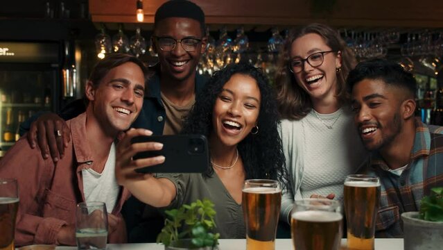 Diverse group of friends taking selfies in restaurant