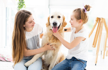 Cute sisters with adorable dog on floor at home