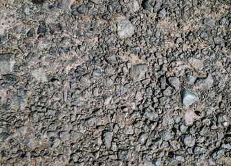 Small cinder stones lie on a dirt road, top view in the rays of the midday sun.