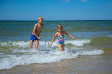 Brother and sister of having fun in water on beach and splashing