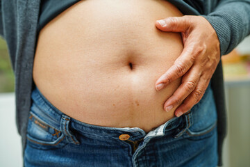 Asian woman show fat belly big size overweight and obesity at office.