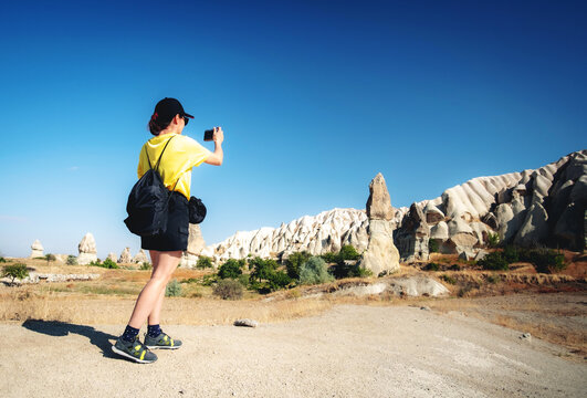 Woman tourist taking pictures of mountains in Cappadocia, Turkey