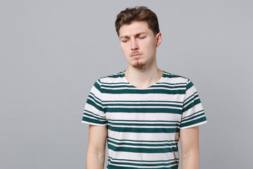 Obraz premium Young sad disappointed upset tired depressed frustrated unhappy caucasian man 20s wear blue striped t-shirt look down isolated on plain gray color background studio portrait. People lifestyle concept.