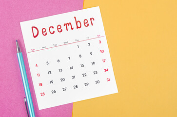December 2022 calendar  with pen on multicolored background.