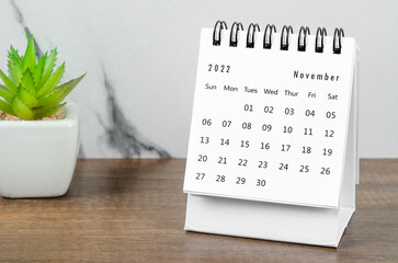 November 2022 desk calendar with plant pot on wooden table.