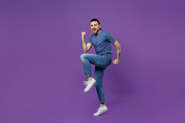 Fototapeta na wymiar Full body young excited man 20s wearing basic blue t-shirt doing winner gesture celebrate clenching fists say yes isolated on plain purple color background studio portrait. People lifestyle concept.