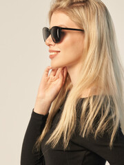 fashionable portrait of a beautiful blonde in dark glasses on a white background and in a dark shirt