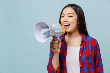 Young smiling woman of Asian ethnicity 20s in checkered shirt hold scream in megaphone announces...