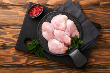Raw chicken thigh fillet without skin with herbs and spices on old wooden background. Farm poultry...