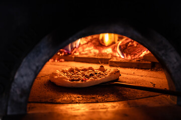 Pizza concept. Preparing traditional italian pizza. Long shovel for pizza, baking dough in a...