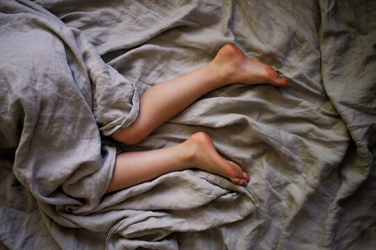 Legs laying in bed with grey sheets