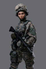 Studio shot of isolated on gray background woman soldier holding rifle.