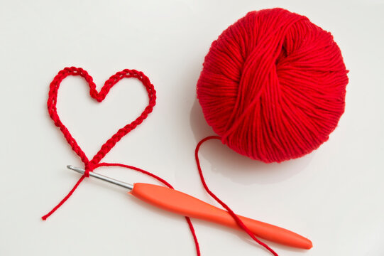 Close up of a wool ball and heart shape on white background. Heart shaped woolen yarn. Love Crochet.