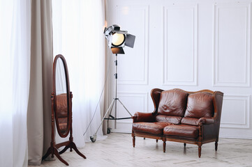White interior with old leather classic sofa and round floor mirror