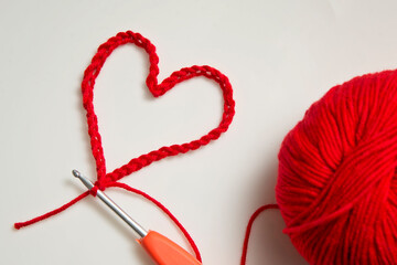 Close up of a wool ball and heart shape on white background. Heart shaped woolen yarn. Love Crochet.