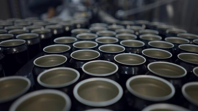 Unsealed Cans Of Beer On Conveyor In Production Line. close up