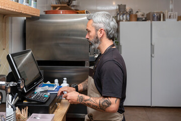 small business, people and service concept - A young waiter at the counter of a small bar or restaurant