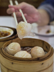 Delicious Chinese dim sum in a chinese restaurant, chopsticks holding steamed shrimp roll