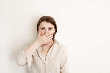 woman covering her mouth with her hand on a white background with bruises on her face