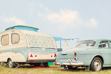 Retro classic car and seventies caravan with flower curtains in two-tone white with green - obrazy, fototapety, plakaty