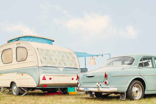 Retro classic car and seventies caravan with flower curtains in two-tone white with green