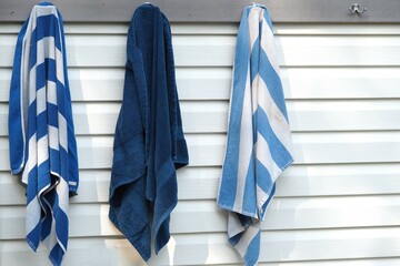 Three towels on the rack drying from the people who came out of the swimming pool.