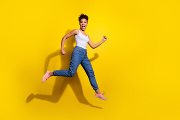 Fototapeta na wymiar Full size photo of energetic active girl hurry rush fast jumping isolated on yellow color background