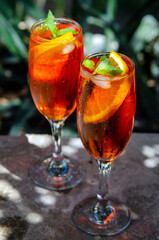 Two glasses of spritz long drink cocktail on stone with sea view background.