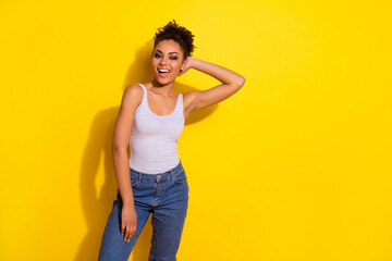 Portrait of satisfied lovely young girl hand touch head hair empty space ad isolated on yellow color background