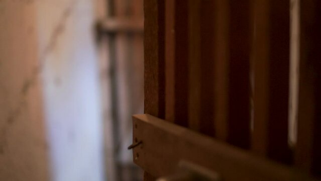 Close up shot of a wooden gate brown gate with blurred old white basement room while entering the basement.
