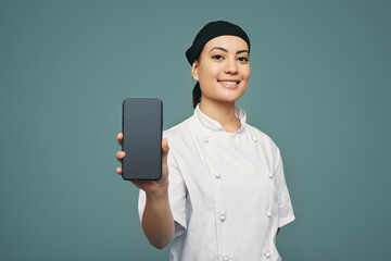 Modern chef displaying a smartphone screen in a studio