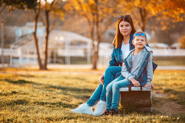 Autumn season. A young mother and son are sitting on a park bench. The concept of a happy childhood and a single mom