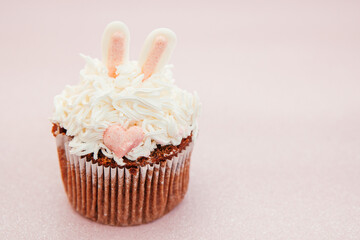Cute bunny cupcake on glitter pink background, card with sweet food and copy space