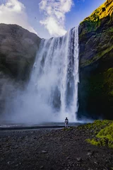 Foto op Aluminium Skogafoss waterfall in Iceland at sunset with someone in front of it © VasileSimion