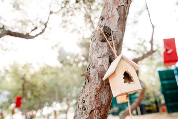 A bird's nest with Christmas decorations hangs from a tree in a forest.
