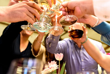 Friends celebrate their happiness with a toast of glasses of white wine, unrecognizable.