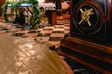Detail of the interior of a dark church, with religious decorations in wood and metal.