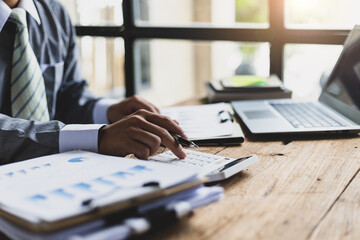 Businessman working on desk office with using a calculator to calculate the finance numbers and calculate about cost to real estate investment and in other, tax system. Finance accounting concept.