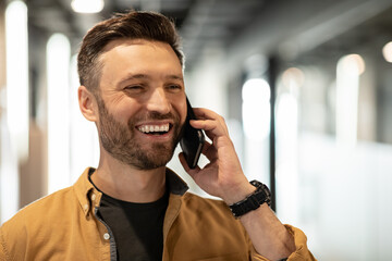 Cheerful Businessman Talking On Cellphone Looking Aside Standing In Office