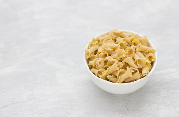 Italian raw pasta campanelle or bluebells made from durum wheat in white bowl on light gray background with copy space