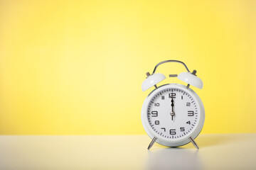 white alarm clock with yellow background, alarm clock as time passing concept for business...