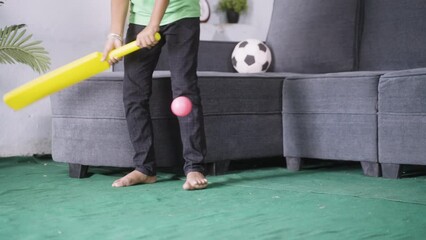 Close up shot of kid playing cricket playing cricket at home - concept of childhood playful activities and development