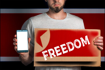 Concept of freedoms and human rights. A man with a cardboard and a phone in his hand. The Flag of...