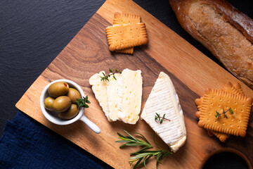 Food concept organic Brie cheese on wooden board on black slate stone with copy space
